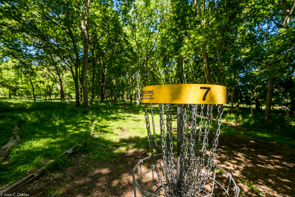 Disc golf basket for hole 7 set among the trees at Roy G. Guerrero course